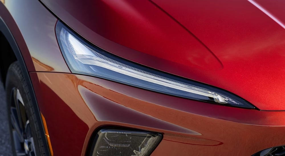A close-up shows the passenger side headlight on a red 2025 Buick Enclave ST.