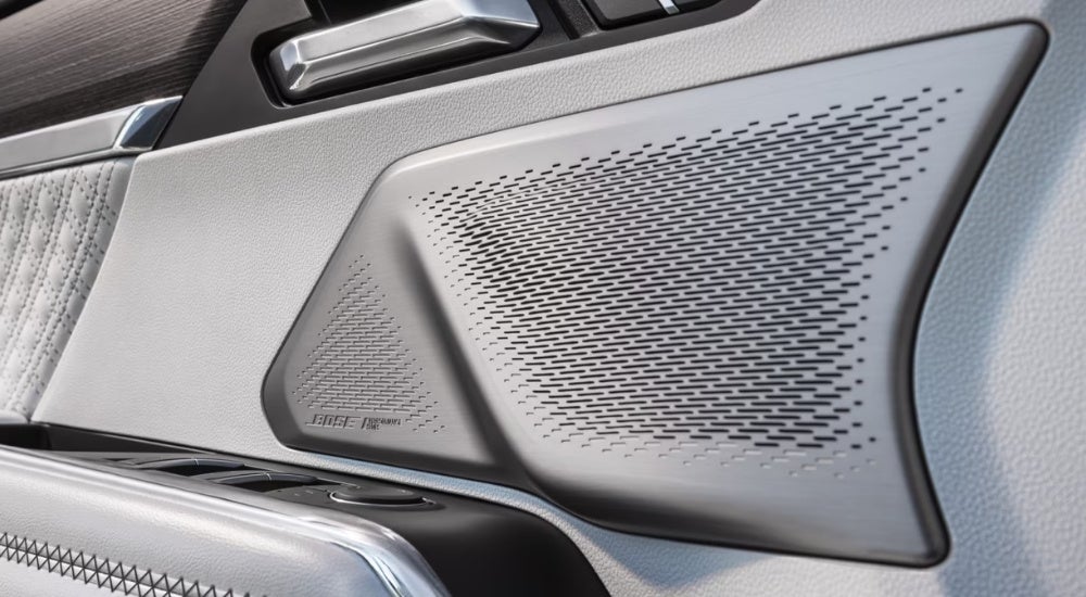 A close up shows a silver Bose speaker in a 2024 GMC Acadia Denali.