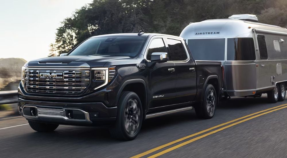 A black 2025 GMC Sierra 1500 Denali for sale near Minneapolis towing an Airstream trailer.