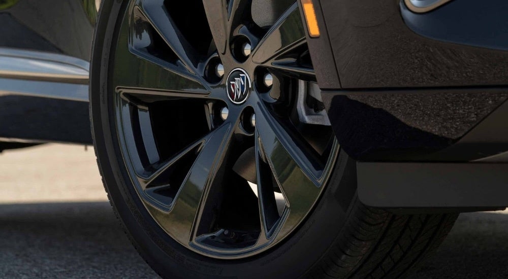 A close-up shows a black wheel on a black 2023 Buick Envision ST.