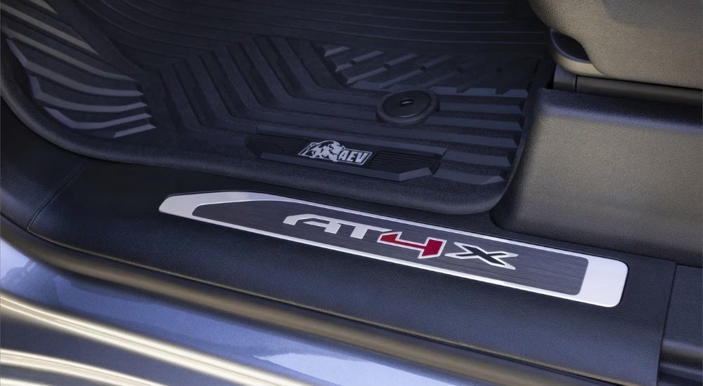A close-up shows a sill guard on a grey 2023 GMC Sierra 1500 AT4X AEV.