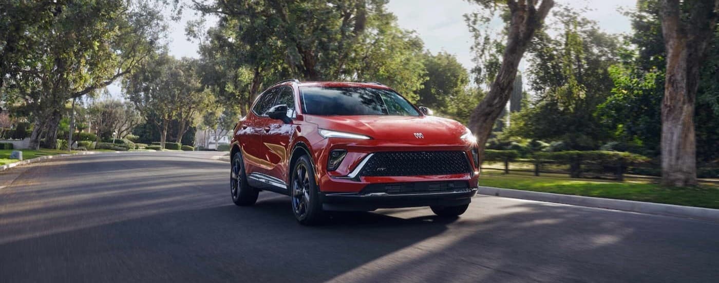 A red 2026 Buick Envision driving in a neighborhood.