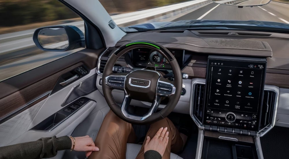 A close-up shows a person using the Super Cruise feature in a 2024 GMC Acadia AT4.