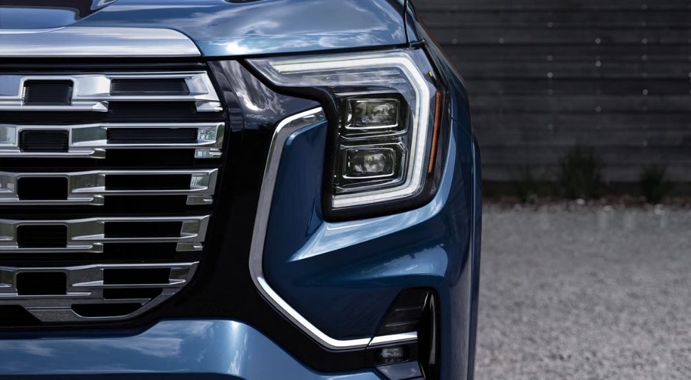 A close-up shows the driver side headlight on a blue 2025 GMC Terrain Denali.