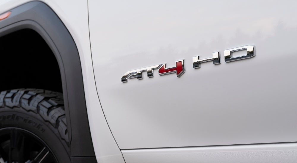 A close-up shows the AT4 badge on a white 2024 GMC Sierra 2500 HD AT4.