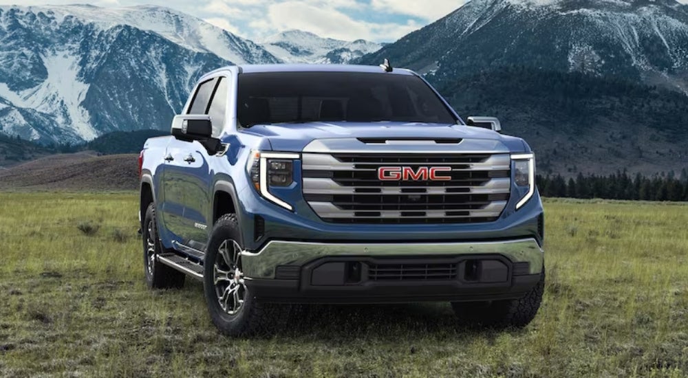 A blue 2025 GMC Sierra 1500 SLE is shown parked on grass.