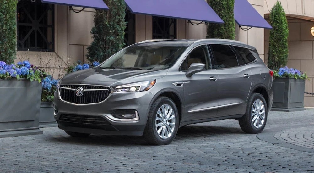 A silver 2020 Buick Enclave is shown in front of a shop.