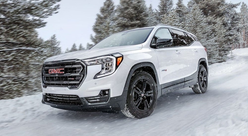 A white 2023 GMC Terrain AT4 is shown off-roading though the snow.