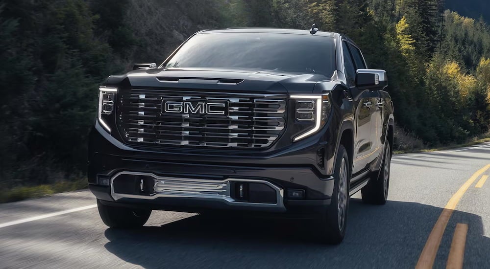 A black 2025 GMC Sierra 1500 Denali Ultimate driving around a bend.