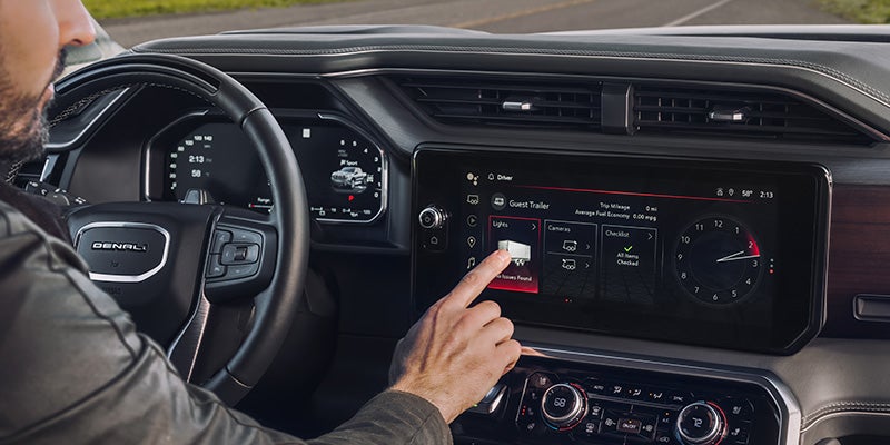 Person using touchscreen infotainment system inside GMC Denali vehicle
