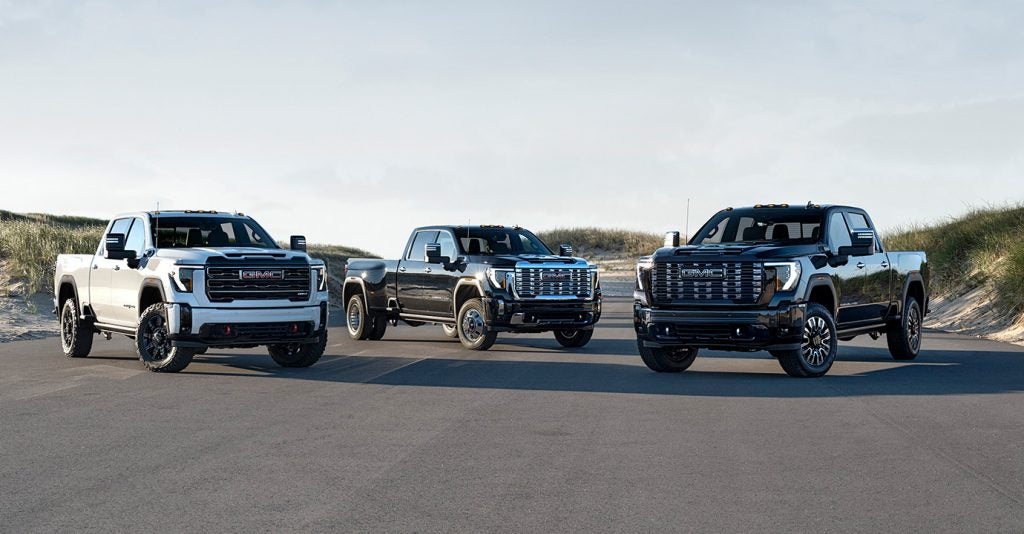 Three GMC trucks parked on a road.
