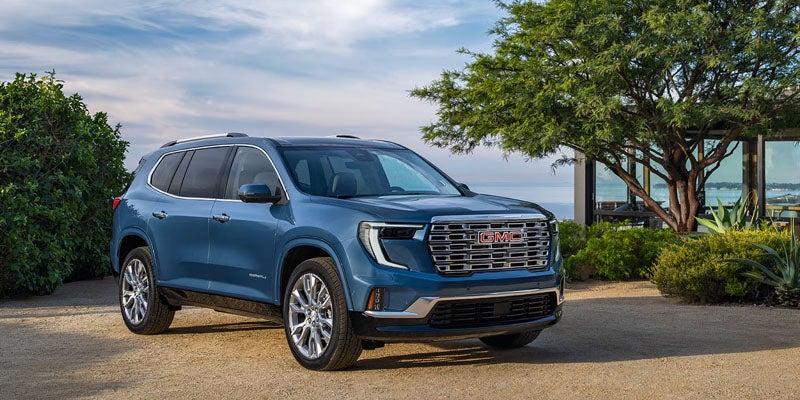 A blue GMC SUV parked in a scenic outdoor setting with trees and greenery