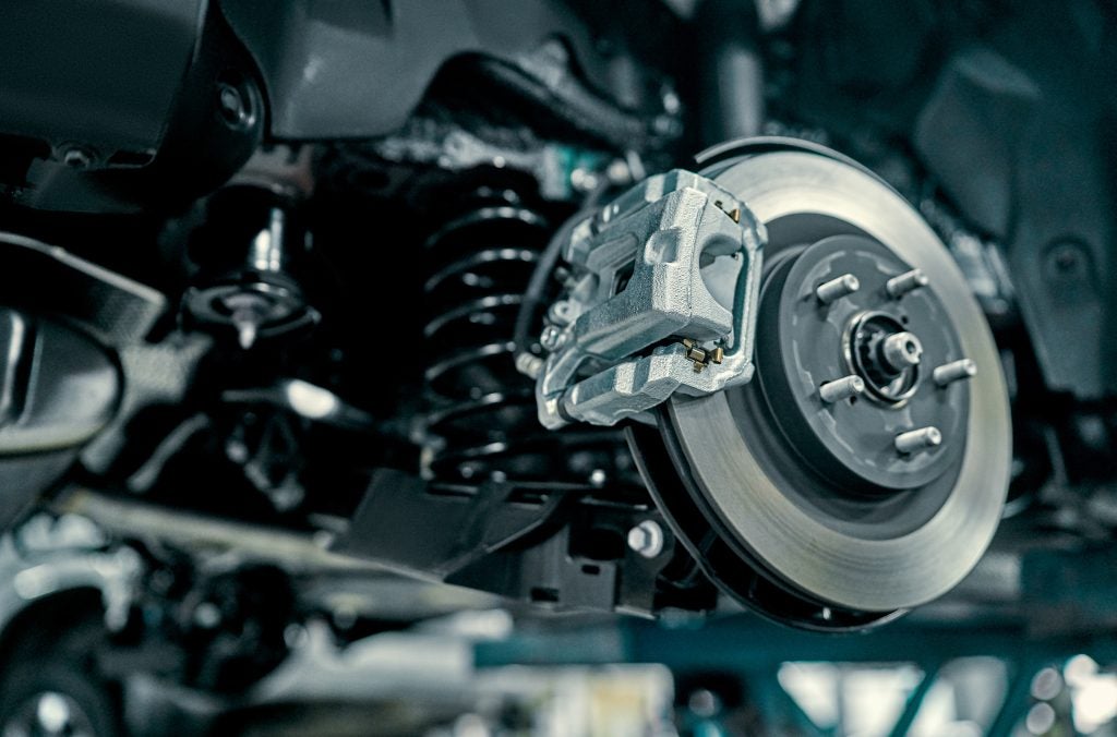 Close-up of a car’s brake assembly, showing the brake rotor, caliper, and suspension components.