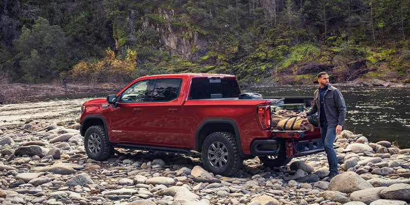 A red GMC Sierra pickup truck parked in a forested area.