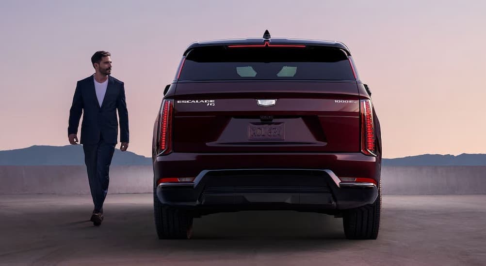 A person walking near a red 2026 Cadillac Escalade IQ.