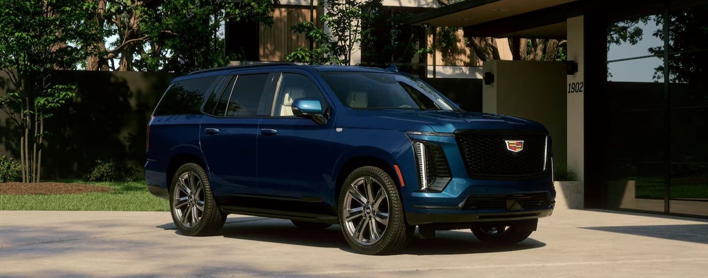A blue 2027 Cadillac Escalade parked near a house.