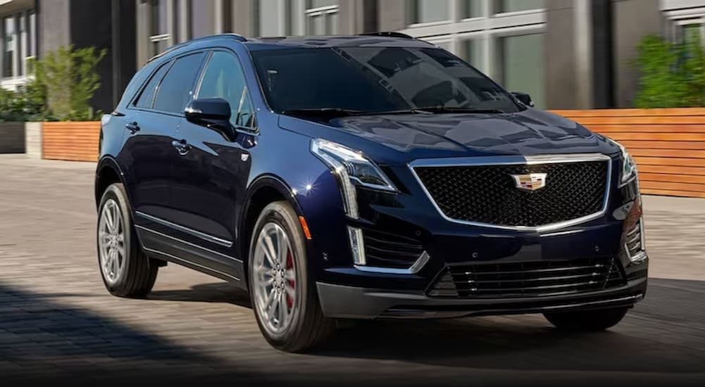 A used blue 2023 Cadillac XT5 for sale near Utica driving in a city.