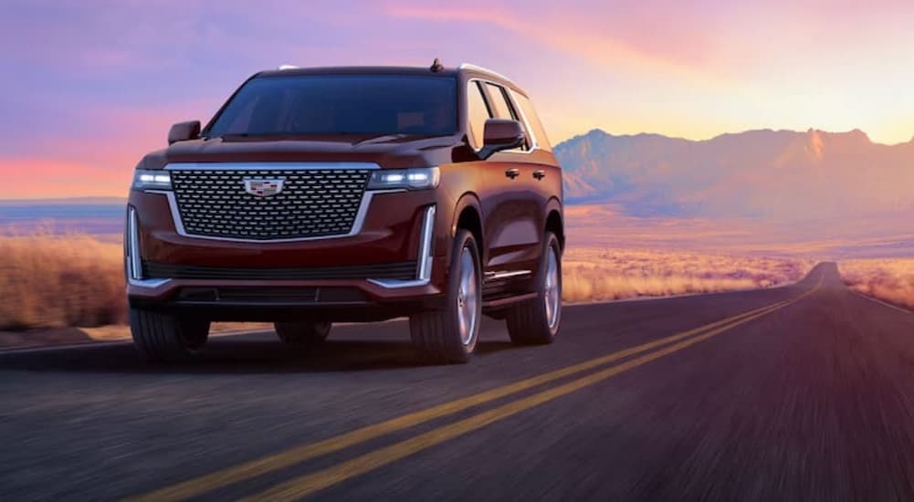 Red 2023 Cadillac Escalade driving on a desert road.