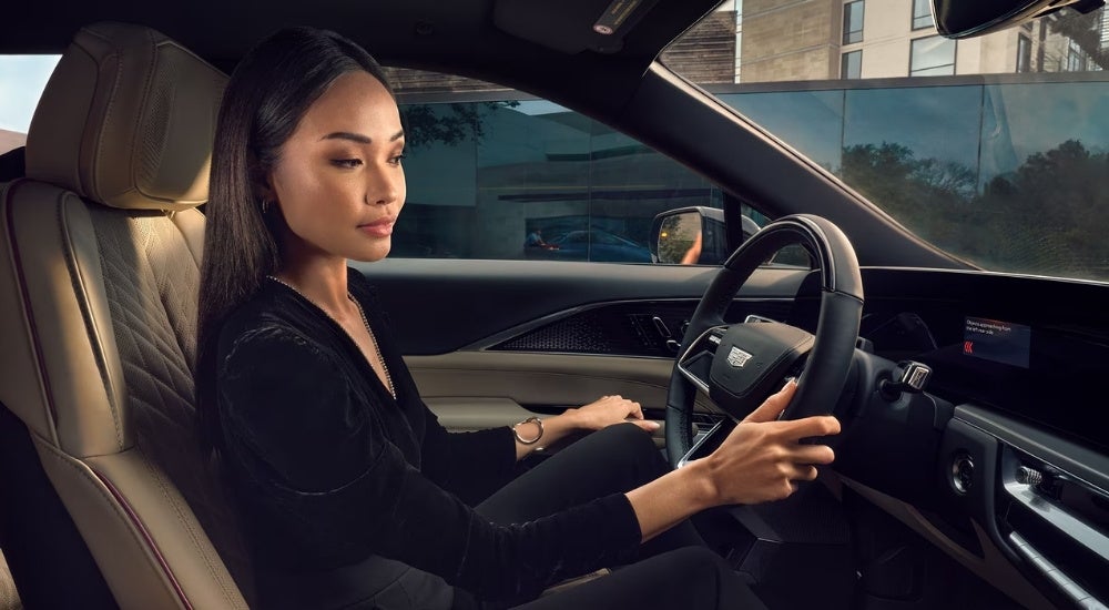 A person is shown on the tan leather drivers seat of a 2025 Cadillac LYRIQ.