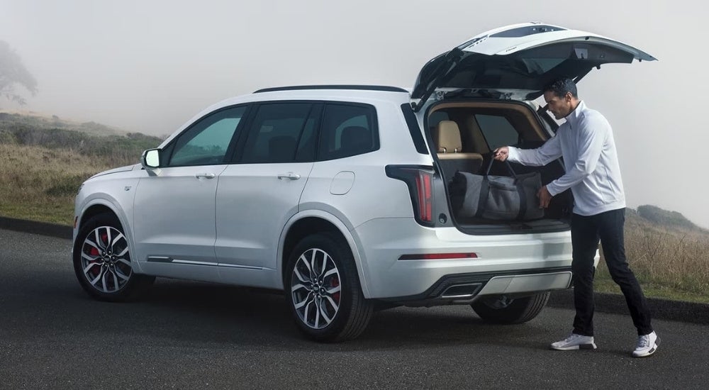 A person is shown stowing a bag in a white 2024 Cadillac XT6.