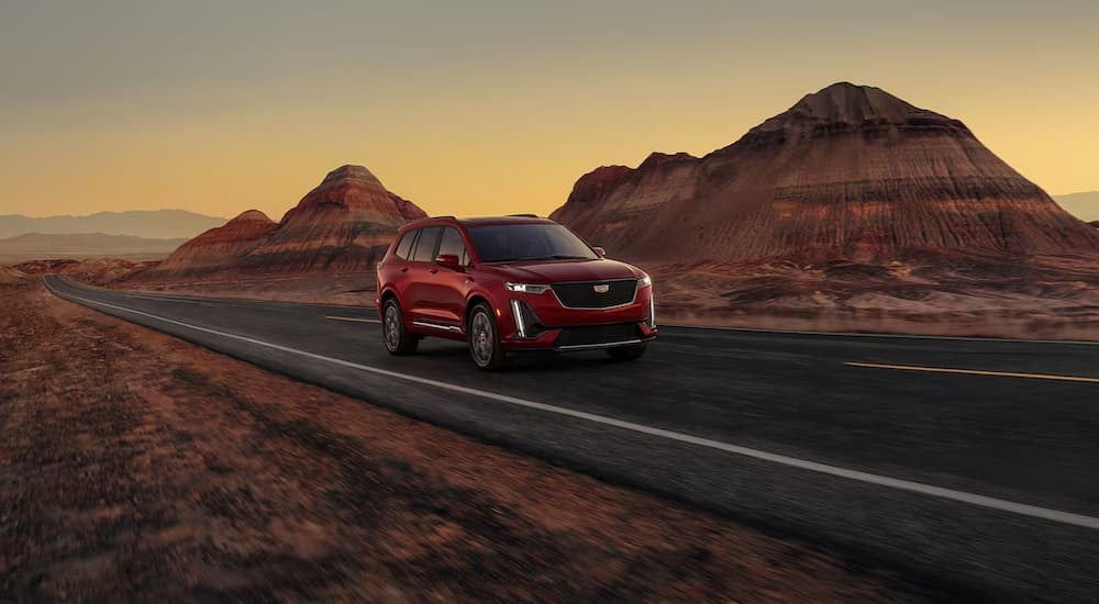 A red 2025 Cadillac XT6 driving on a highway.