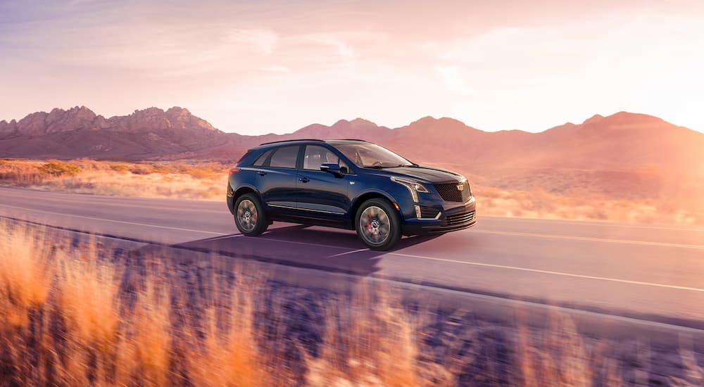 A blue 2025 Cadillac XT5 driving on an open road.