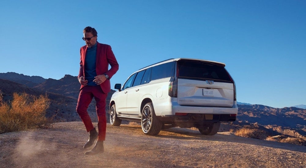 A person is shown standing near a silver 2023 Cadillac Escalade.