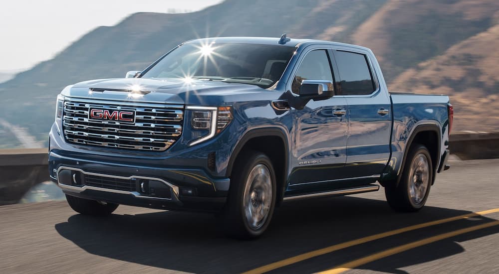Blue 2022 GMC Sierra 1500 driving down a winding road.