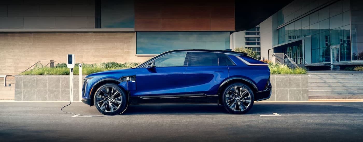 A blue 2024 Cadillac LYRIQ charging in a city.