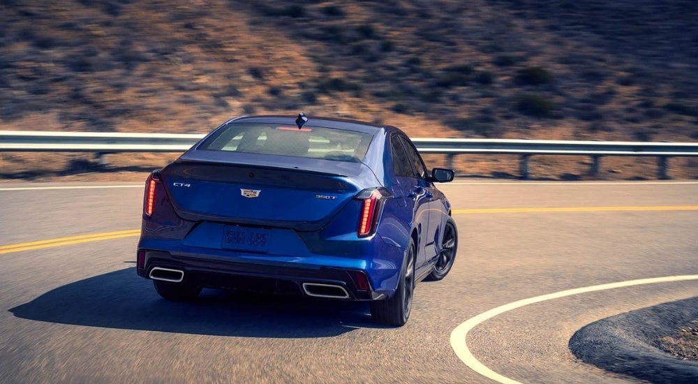 A blue 2024 Cadillac CT4 is shown rounding a corner.