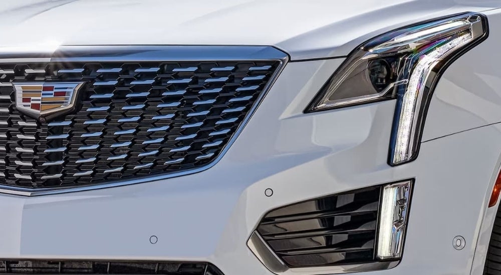 A close-up shows driver side headlight on a white 2023 Cadillac XT5.