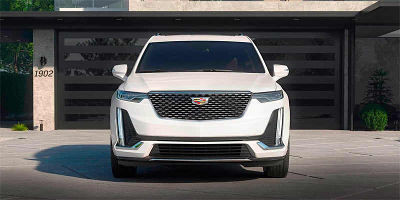 A white Cadillac SUV parked in front of a modern house with a sleek driveway