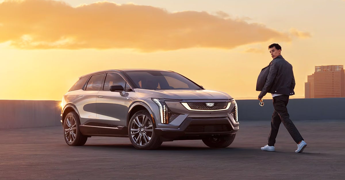 2025 Cadillac Optiq parked in an open area with a man walking towards the vehicle