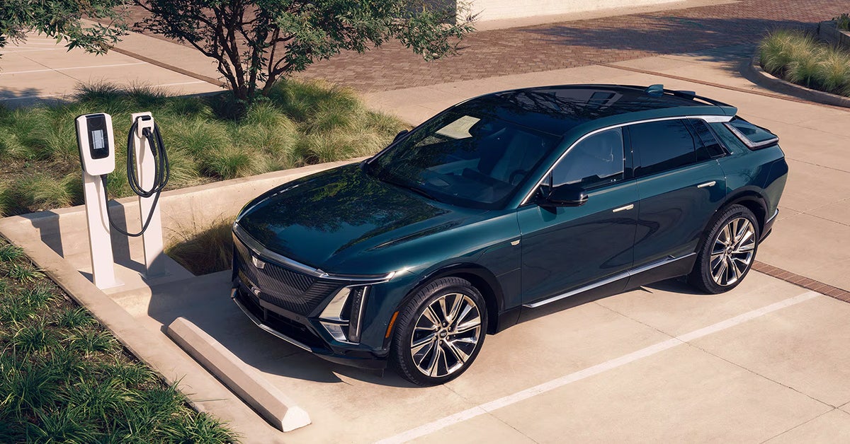 Cadillac lyriq ev suv parked next to a charger