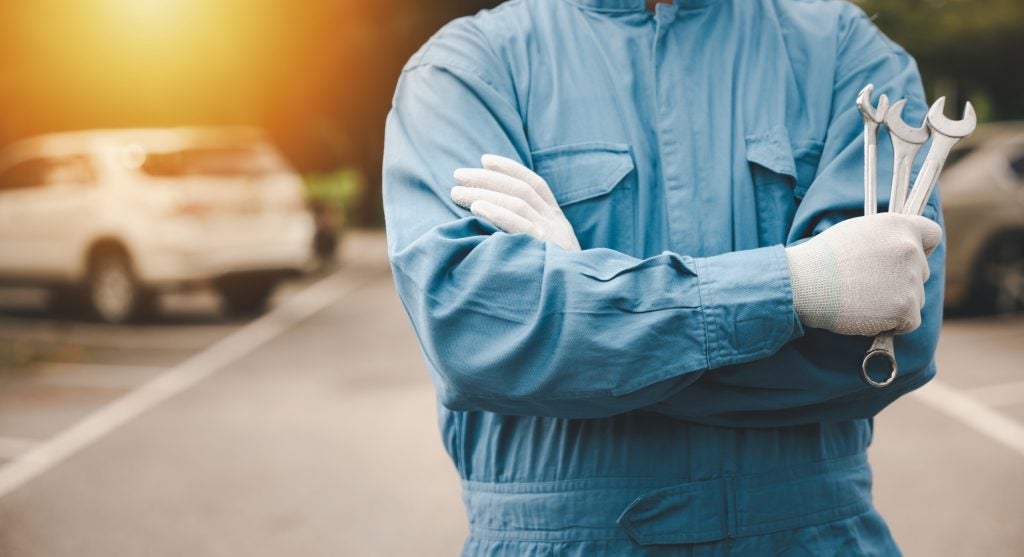 Automotive technician holding tools during vehicle service inspection.