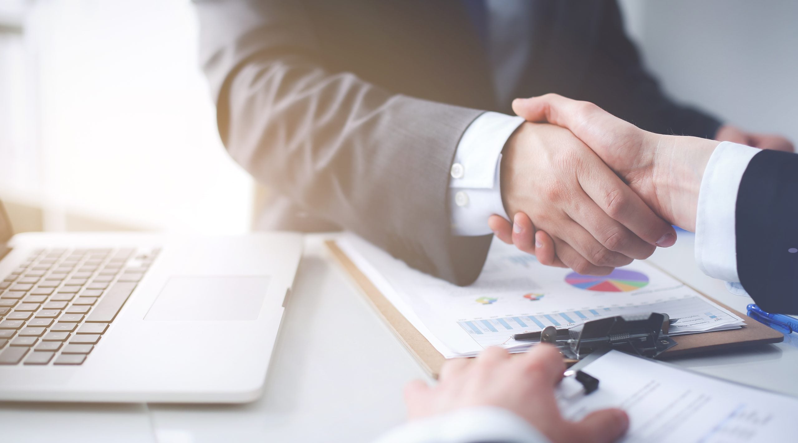 Two people shaking hands over business documents