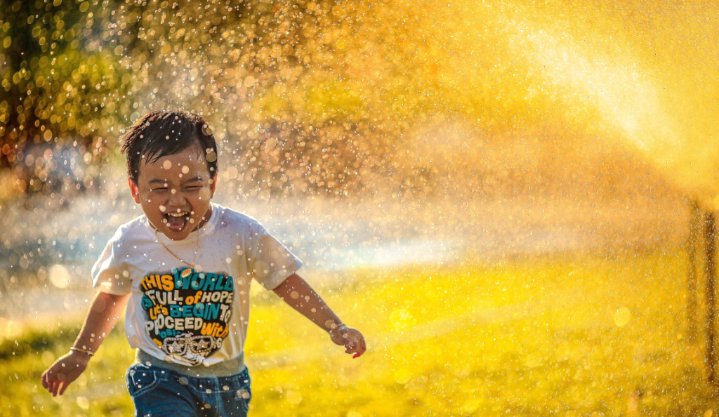 kid playing in sprinkler
