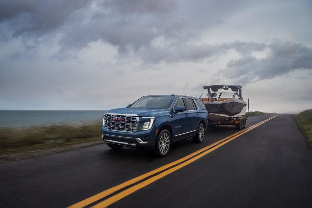 2026 GMC Yukon Denali in Downpour Metallic Trailering Boat on highway