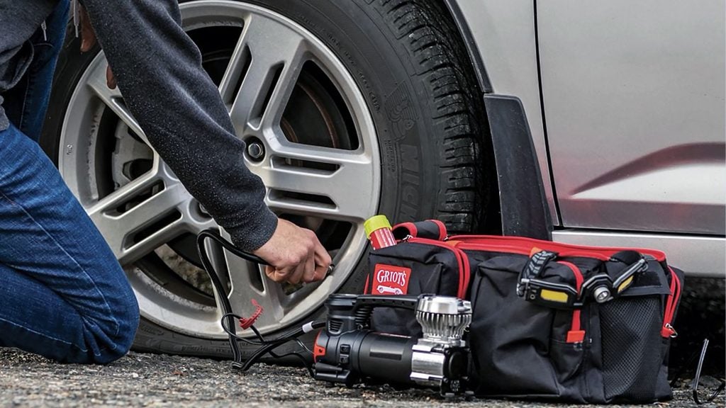 Emergency roadside kit being used to inflate flat tire