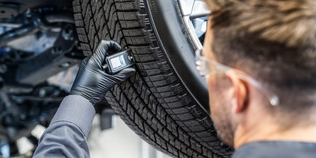 close-up of tire tread being checked by service technician