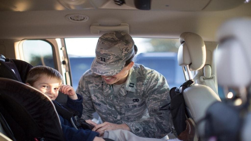 military service member buckling child into car seat