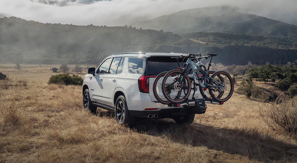 Rear of a white 2027 GMC Yukon with a bike rack parked off-road.