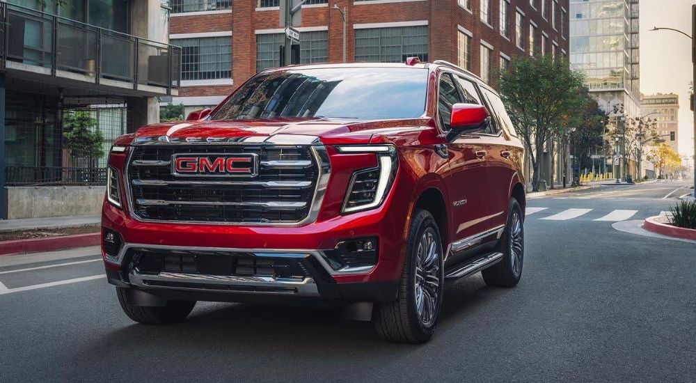 Red 2027 GMC Yukon Elevation driving on a paved road.