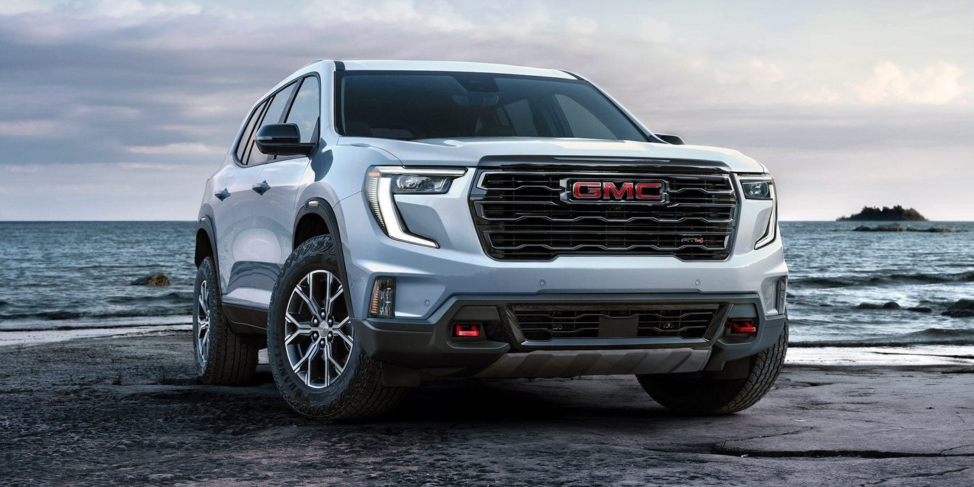 White 2027 GMC Acadia AT4 parked on a rocky shoreline, at Ross Downing GMC in Hammond, LA