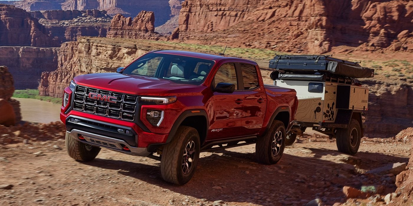 Red 2026 GMC Canyon towing a small off-road camper trailer through red rock country; Canyon towing at Ross Downing GMC in Hammond, LA