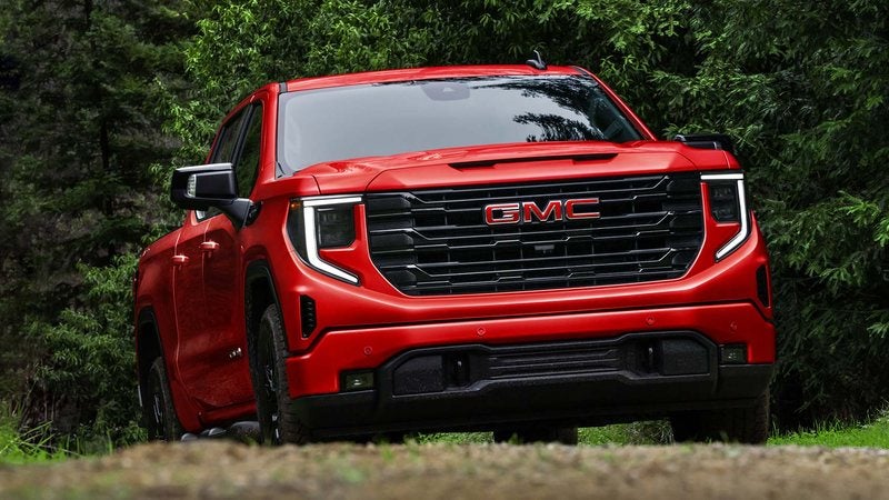Red 2026 GMC Sierra 1500 parked in a forest clearing; GMC Sierra 1500 deals at Ross Downing GMC in Hammond, LA
