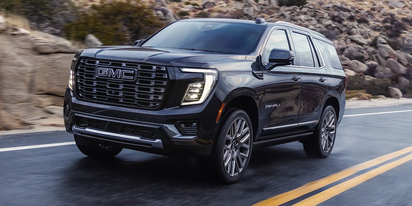 Black 2026 GMC Yukon Denali driving on a two-lane highway; GMC Yukon engines and towing at Ross Downing GMC in Hammond, LA