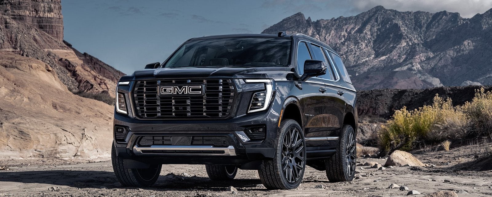 Black 2026 GMC Yukon Denali Ultimate parked on a rocky desert trail; new GMC Yukon SUVs for sale at Ross Downing GMC in Hammond, LA
