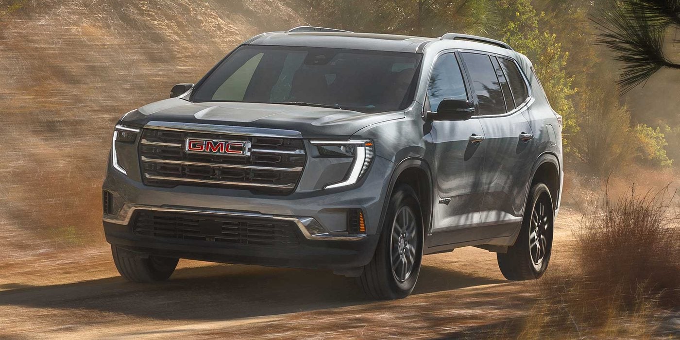 Gray 2027 GMC Acadia driving along a dusty trail; GMC Acadia engine, AWD and towing at Ross Downing GMC in Gonzales, LA