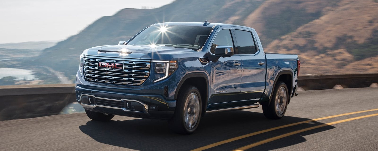 Blue 2026 GMC Sierra 1500 Denali Crew Cab on a coastal highway; new GMC Sierra 1500 trucks for sale at Ross Downing GMC in Gonzales, LA
